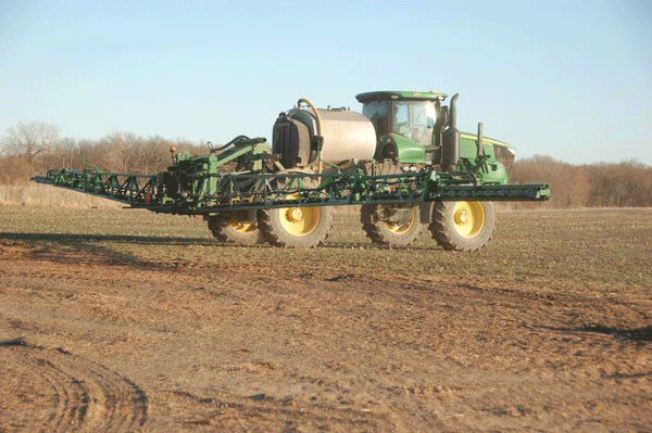 A tractor pulling a sprayerDescription automatically generated